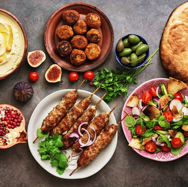 arabic and middle eastern dinner table hummus, tabbouleh salad, fattoush salad, pita, meat kebab, falafel, baklava, pomegranate set of arabian dishestop view, flat lay