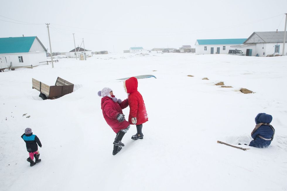 Kinderen spelen op een berg sneeuw in Tastubek in Kazachstan waar de verbetering van de economische omstandigheden hand in hand gaat met de verbetering van de waterkwaliteit in het meer