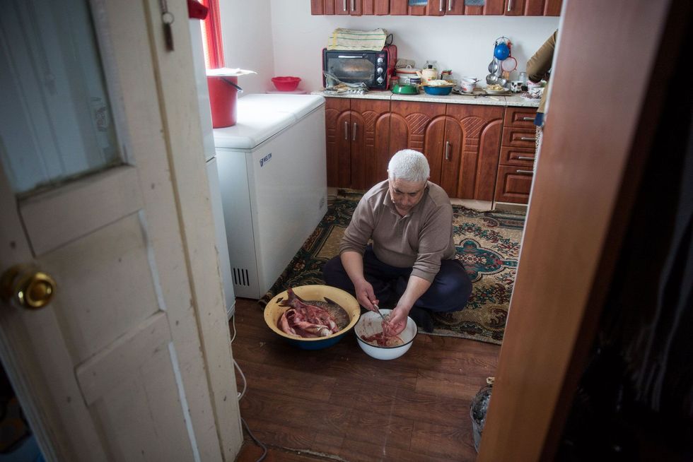 De 45jarige Kidirbai Ibragimov bereidt vis in zijn woning in Tastubek