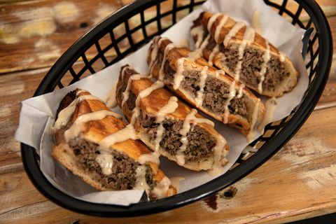 arayes ground beef stuffed pita drizzled with tahini served in a plastic basket on a wooden table