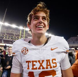 a young man in a texas football uniform smiling as he walks off the field