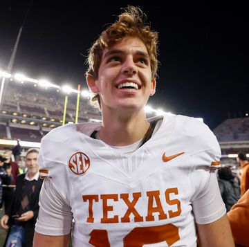 a young man in a texas football uniform smiling as he walks off the field