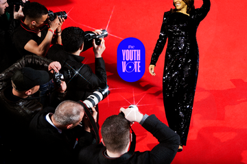 a red carpet event featuring a woman in a sequined black dress surrounded by photographers