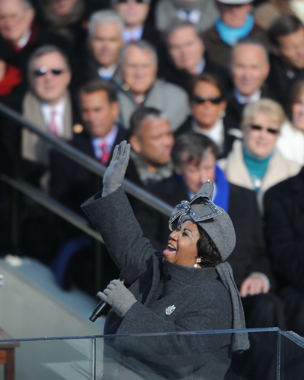 aretha franklin sings into a wireless microphone she holds in one hand as her other hand raises updward