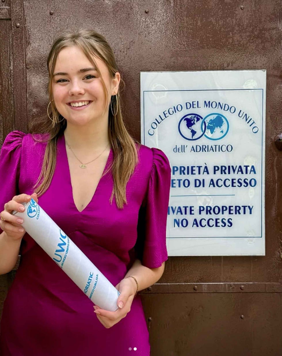 young woman holding a rolled document in front of a sign indicating private property