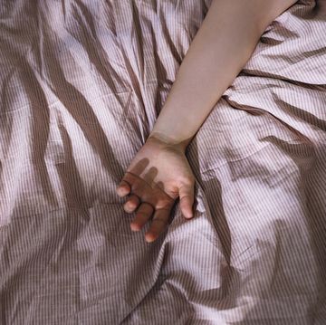 arm of an anonymous woman sleeping in bed from above