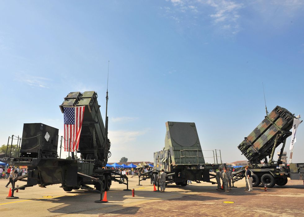 a us army patriot surface to air missile system with one truck on the left displaying an american flag