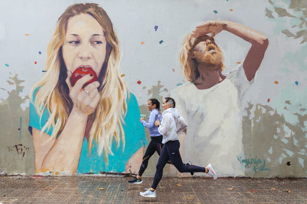 dos runners corren delante de un mural gigante en las calles de barcelona