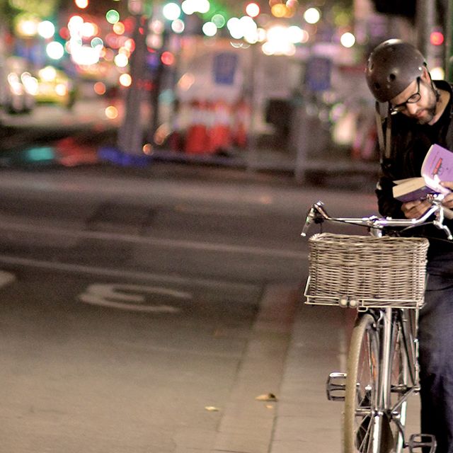cyclist reading a book on street at night