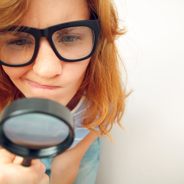 woman looking at pores with magnifying lens