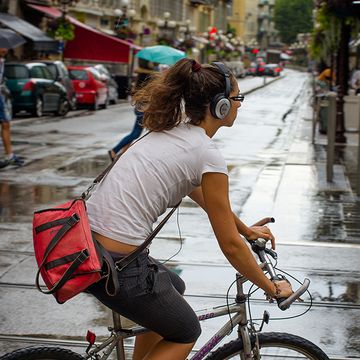 A woman riding a bike with headphones on.
