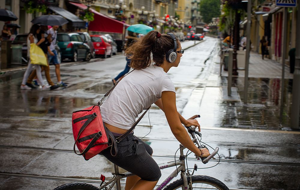 A woman riding a bike with headphones on.