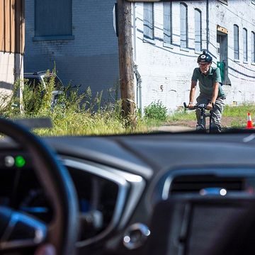 A cyclist passes a pilot model of the Uber self-driving car
