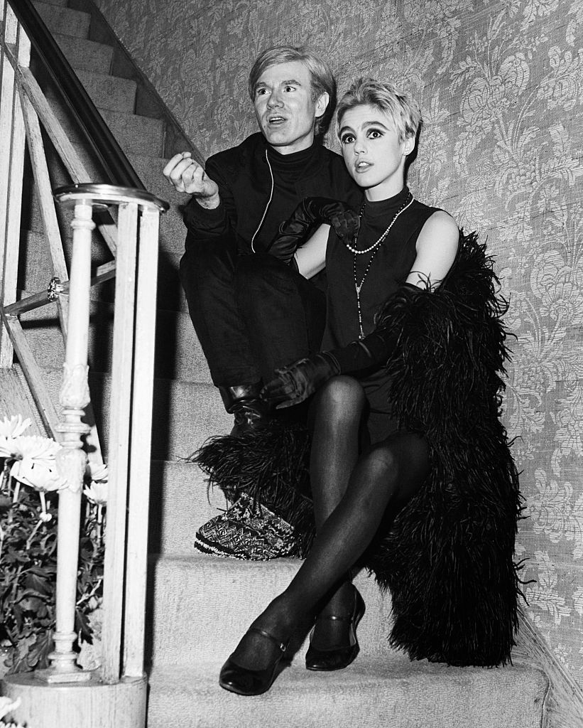 andy warhol and actress edie sedgwick seated on stairs