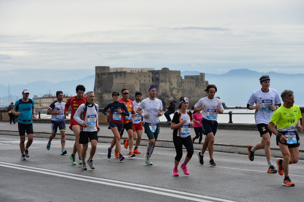 Participants running in a marathon with a historic castle in the background