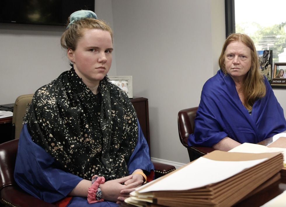 two women sitting at a desk and in an office room with concerned looks on their faces