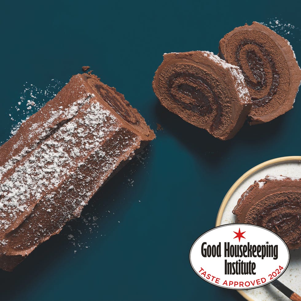 chocolate roll cake with a slice taken out dusted with powdered sugar