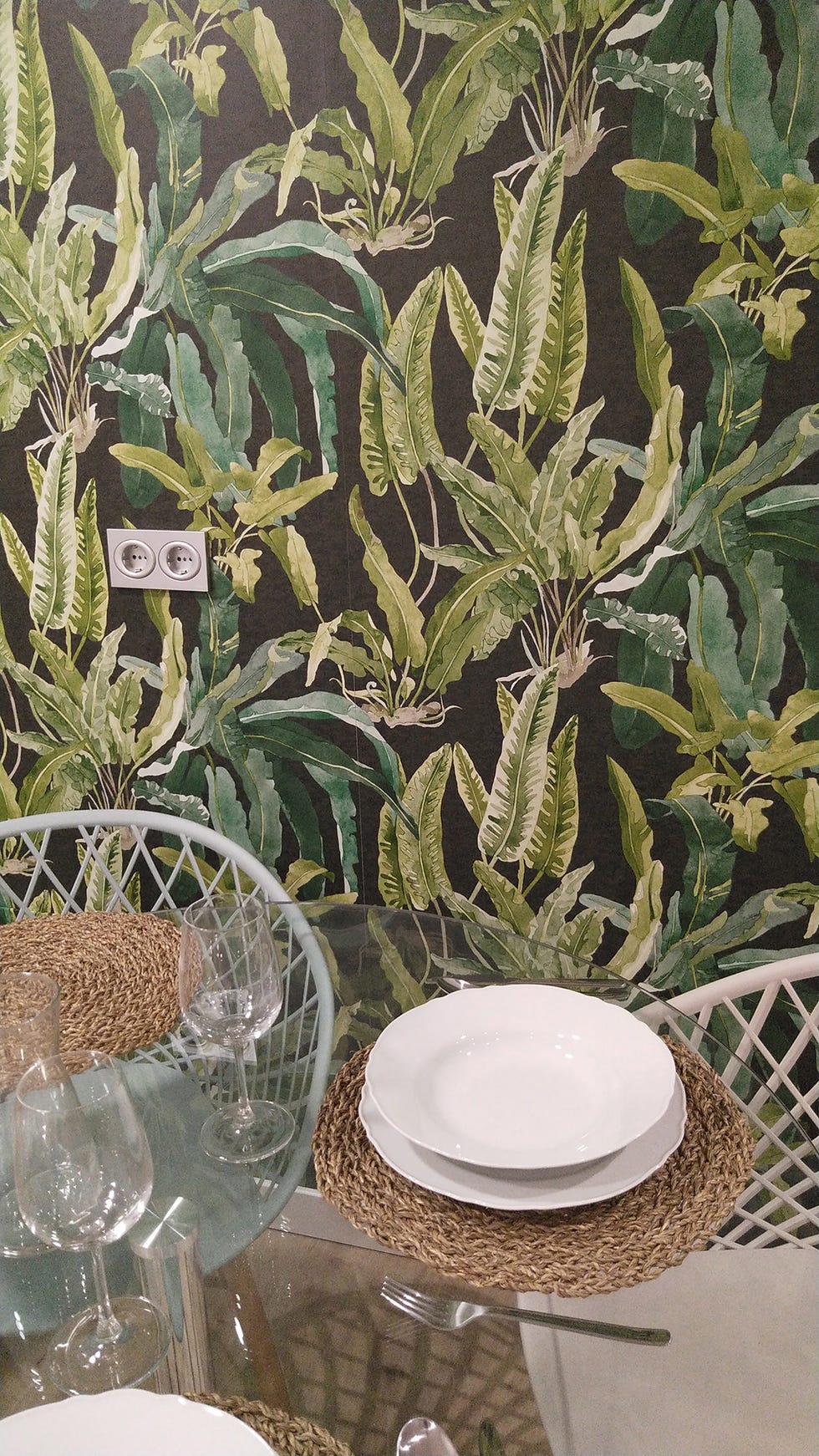 mesa de comedor de cristal y papel pintado con motivos botánicos