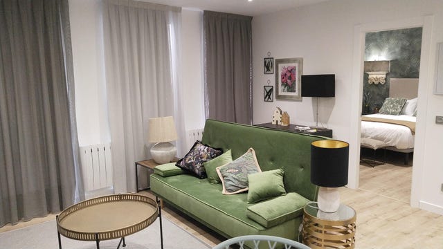 salón con sofá de terciopelo verde y mesa de centro dorada