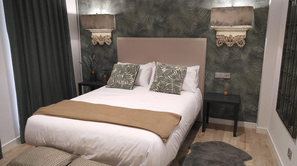 dormitorio decorado en tonos verdes con papel pintado botánico y apliques ornamentales