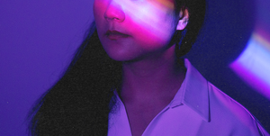 a woman against a dark purple background with a ray of light across her face
