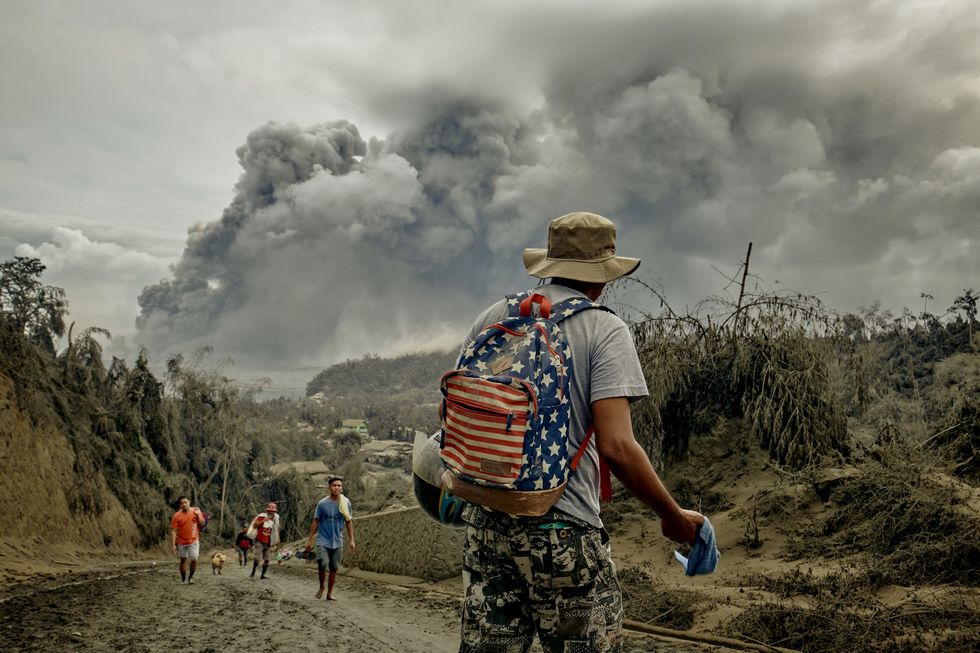 Bewoners ontvluchten hun dorp terwijl aswolken van de uitbarsting van de vulkaan Taal boven het gebied hangen 13 januari