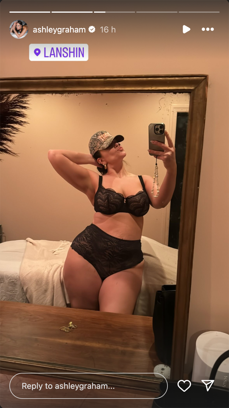 Ashley Graham wears *only* a black lace lingerie set and camo cap