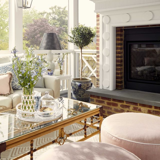 outdoor screened porch, fire place, pink ottomans, gold and glass coffee table