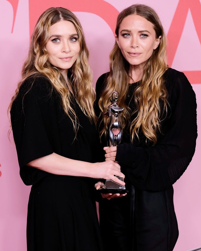 ashley and mary kate olsen holding a trophy from an award show