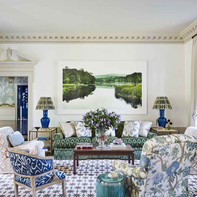 a serene landscape photograph relaxes grand moldings with a masterful new modernity and the walls are white and there is a green velvet sofa