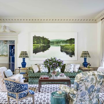 a serene landscape photograph relaxes grand moldings with a masterful new modernity and the walls are white and there is a green velvet sofa