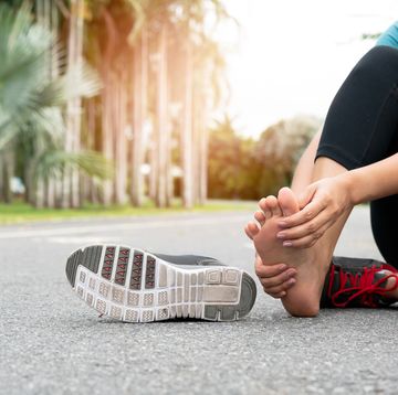 asia woman massaging her painful foot while exercising running