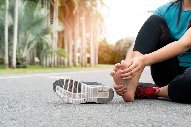 asia woman massaging her painful foot while exercising running