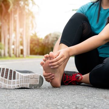 asia woman massaging her painful foot while exercising running