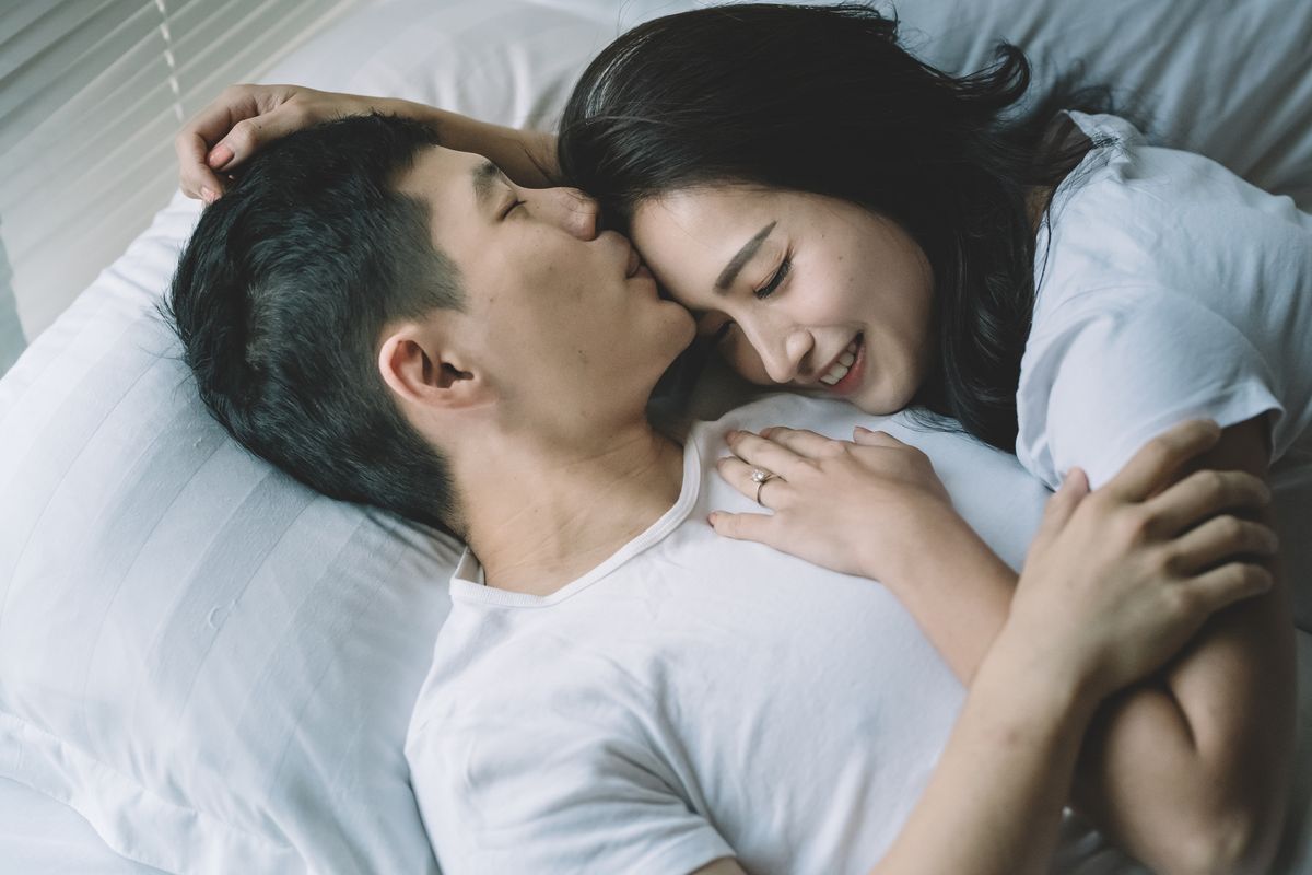 asian chinese couple on bed where the boyfiend kissing his girlfriend forehead