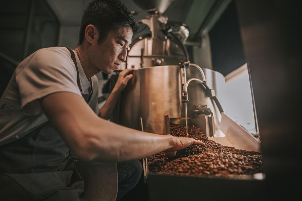 ロースターでコーヒー豆を焙煎する男性