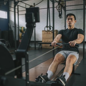 asian chinese gay man exercising on rowing machine in a gym