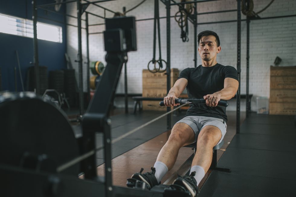 asian chinese gay man exercising on rowing machine in a gym