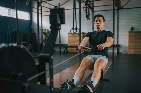 asian chinese gay man exercising on rowing machine in a gym