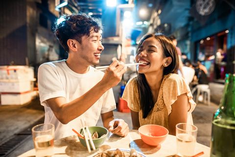 asian couple enjoying street food in hong kong