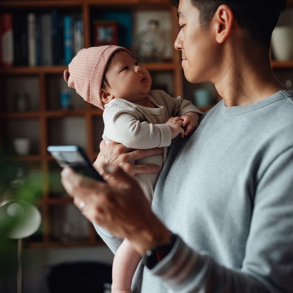 asian father taking care of his baby while working from home
