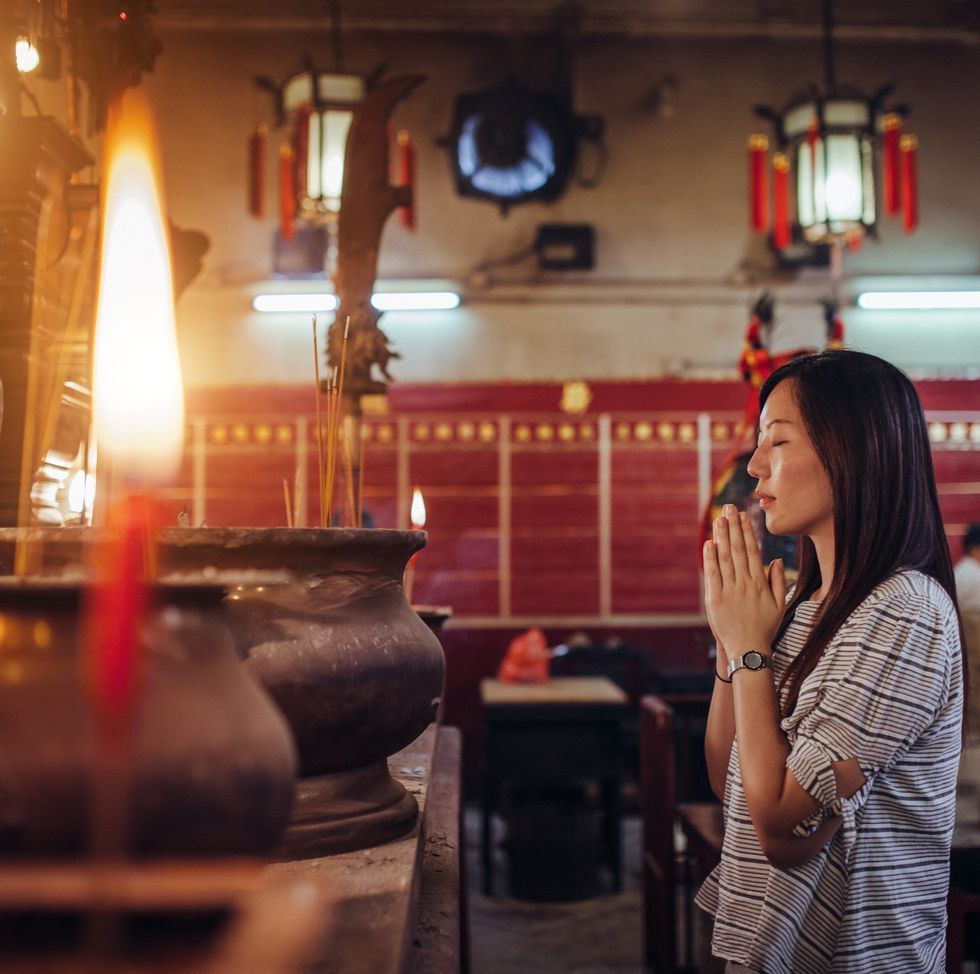 asian female praying sincerely in a chinese temple