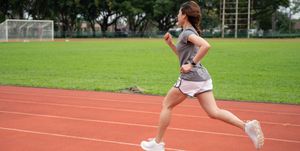 asian female runner doing her workout by sprinting in GEL-Quantum running track