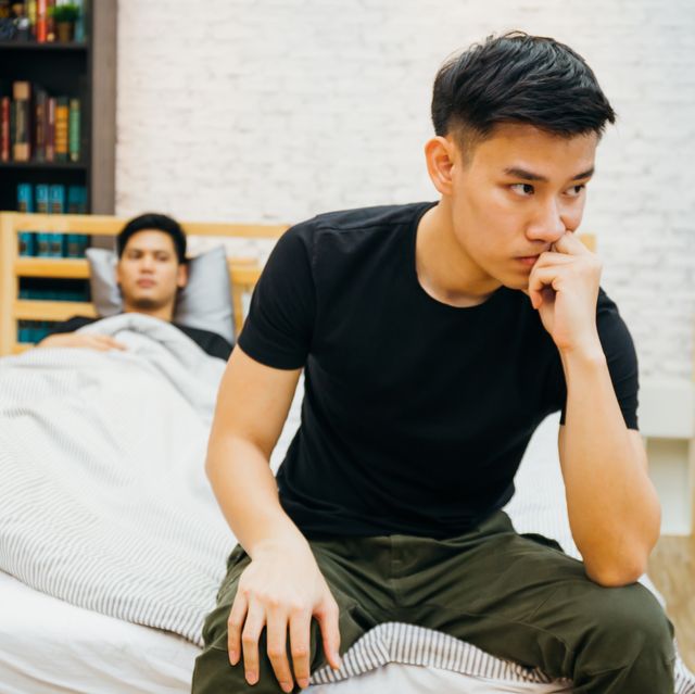 Asian gay couple having argument with each other in bedroom. Thoughtful gay man having stress while another is sleeping - Homosexual love concept