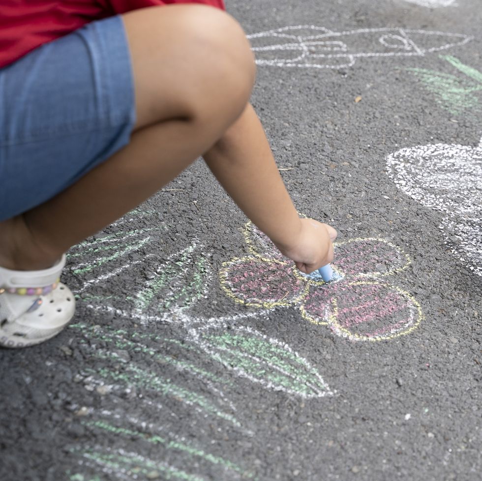 asian girl drawing with sidewalk chalk