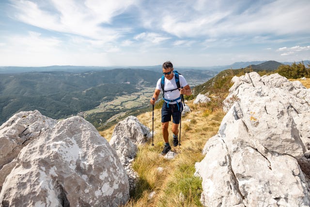 asian mature adult climbing rocky terrain in the mountains