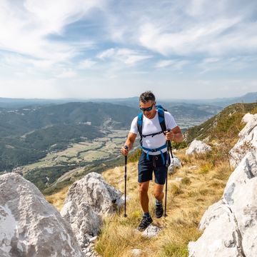 asian mature adult climbing rocky terrain in the mountains