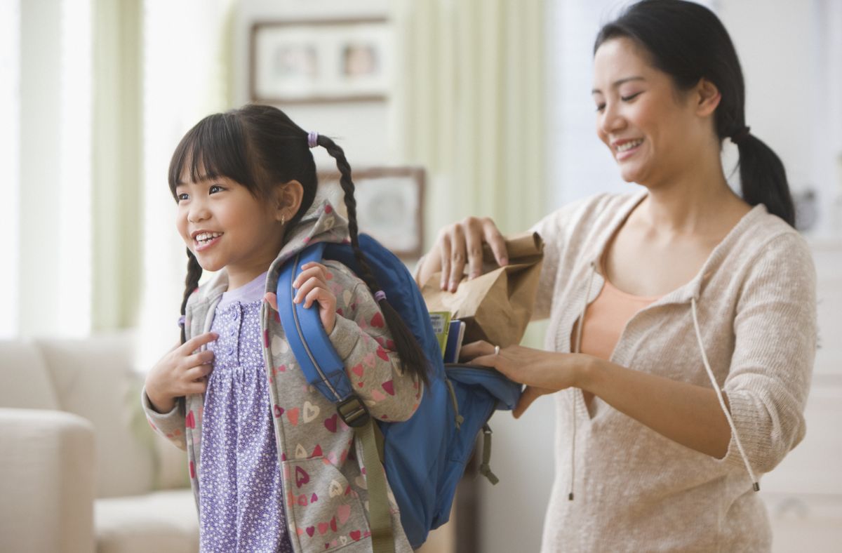asian mother helping daughter get ready for school