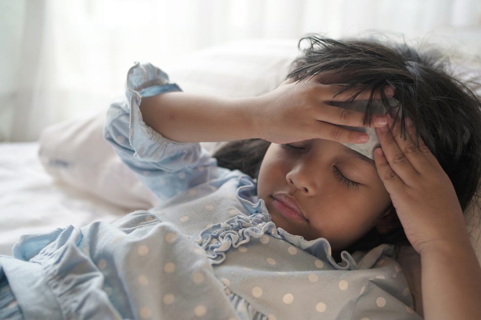 niña con un trapo húmedo en la cabeza para aliviar la cefalea