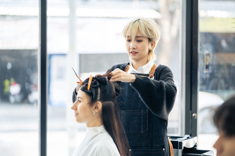 asian professional female stylist cutting woman's hair in salon the woman hairdresser using scissors cut the young girl sitting in the shop looking at mirror with smile beauty salon business concept